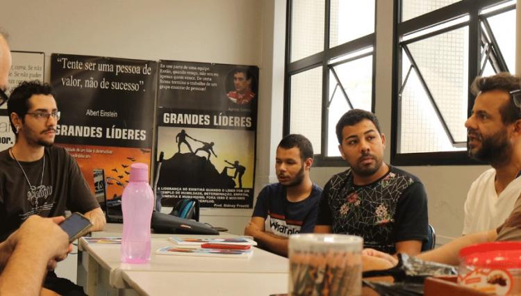 Voluntários reunidos envolta de mesa debatendo.